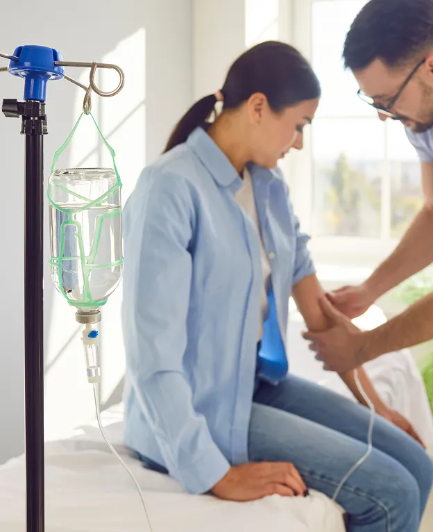 Healthcare professional preparing a patient for IV infusion therapy in a bright clinical room