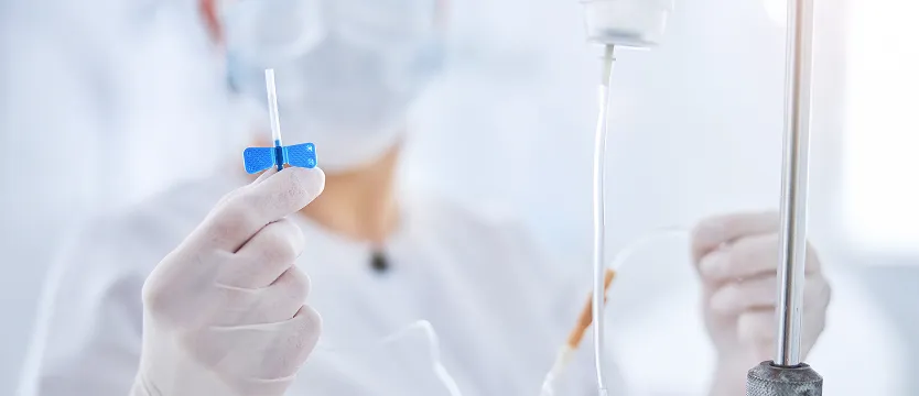 Healthcare professional preparing an IV butterfly needle in a clinical infusion setting