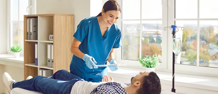 Nurse reviewing a patient's chart during an infusion appointment in a bright clinical setting