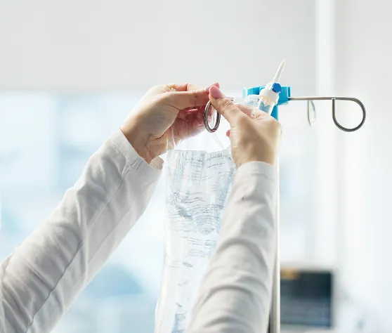 Man receiving IV vitamin infusion while relaxing on a clinic bed, holding water in a modern wellness setting