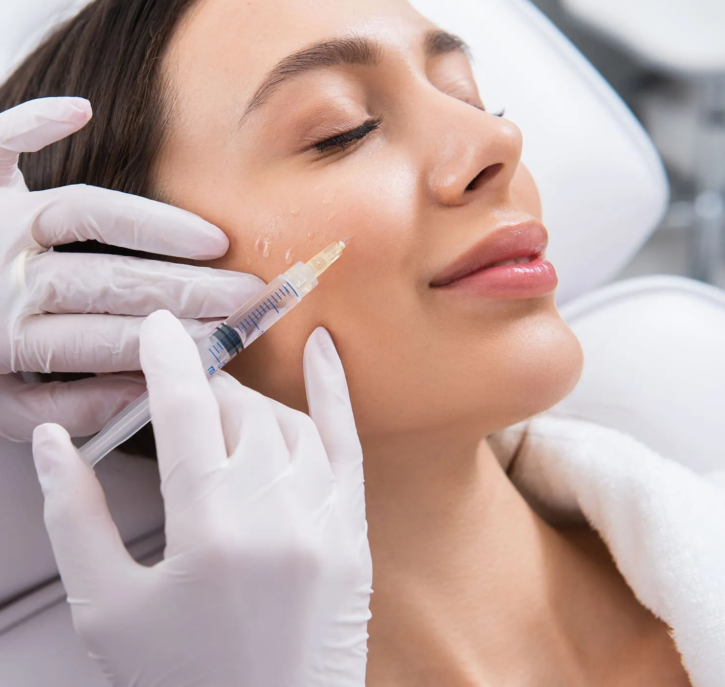 Aesthetic injector preparing a dermal filler treatment for a relaxed patient