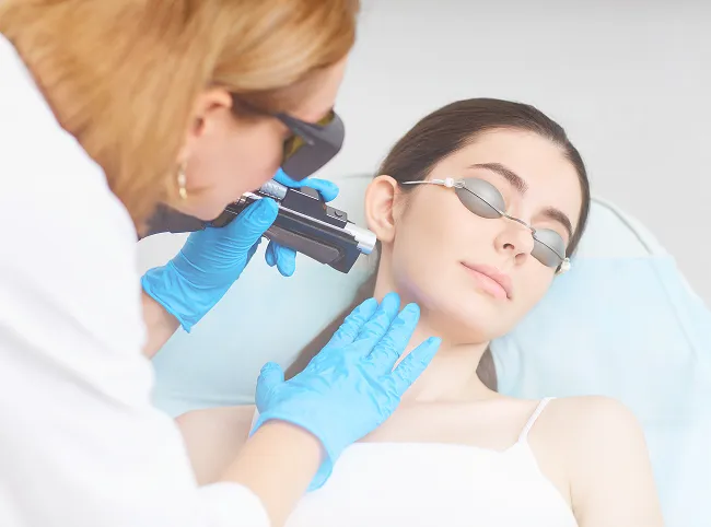 Technician performing laser hair removal on a patient's face in a clinical setting