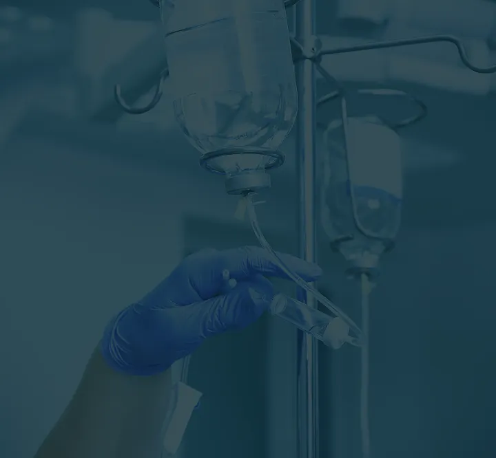 Gloved hand preparing IV infusion bag for medical infusion therapy