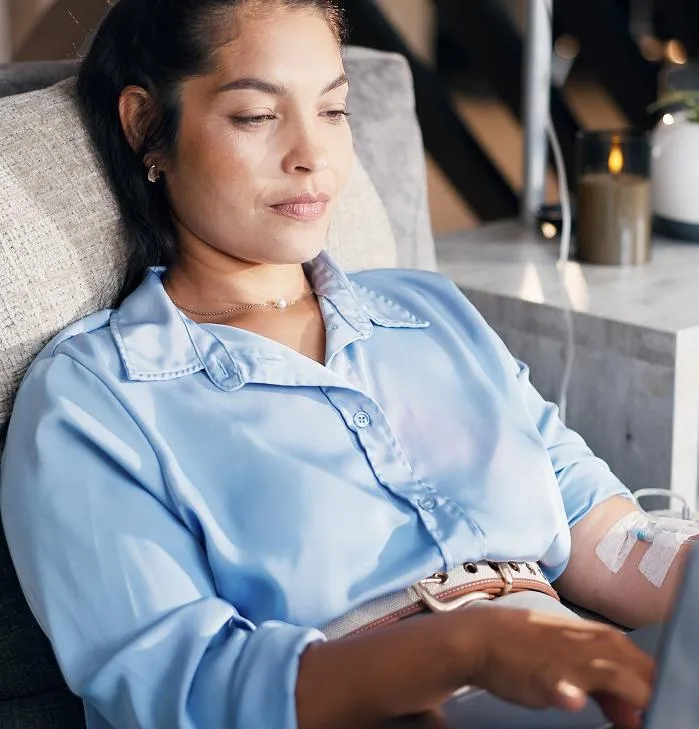 Patient receiving infusion therapy while working comfortably on a laptop